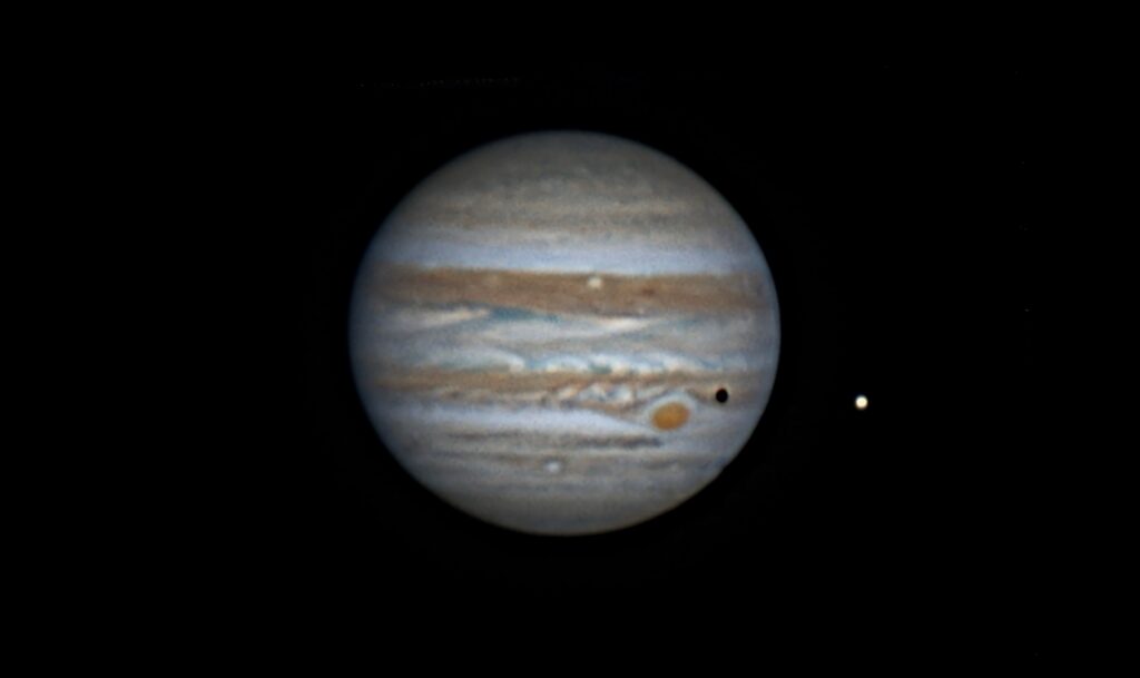 Jupiter showing its cloud bands, the Great Red Spot, Io beside the planet and Io’s shadow crossing the clouds.
