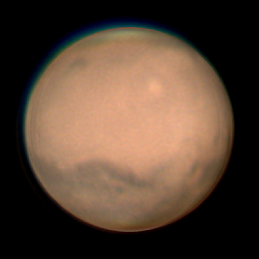 Mars during its 2022 apparition, showing its orange surface, dark markings and a pale polar region.